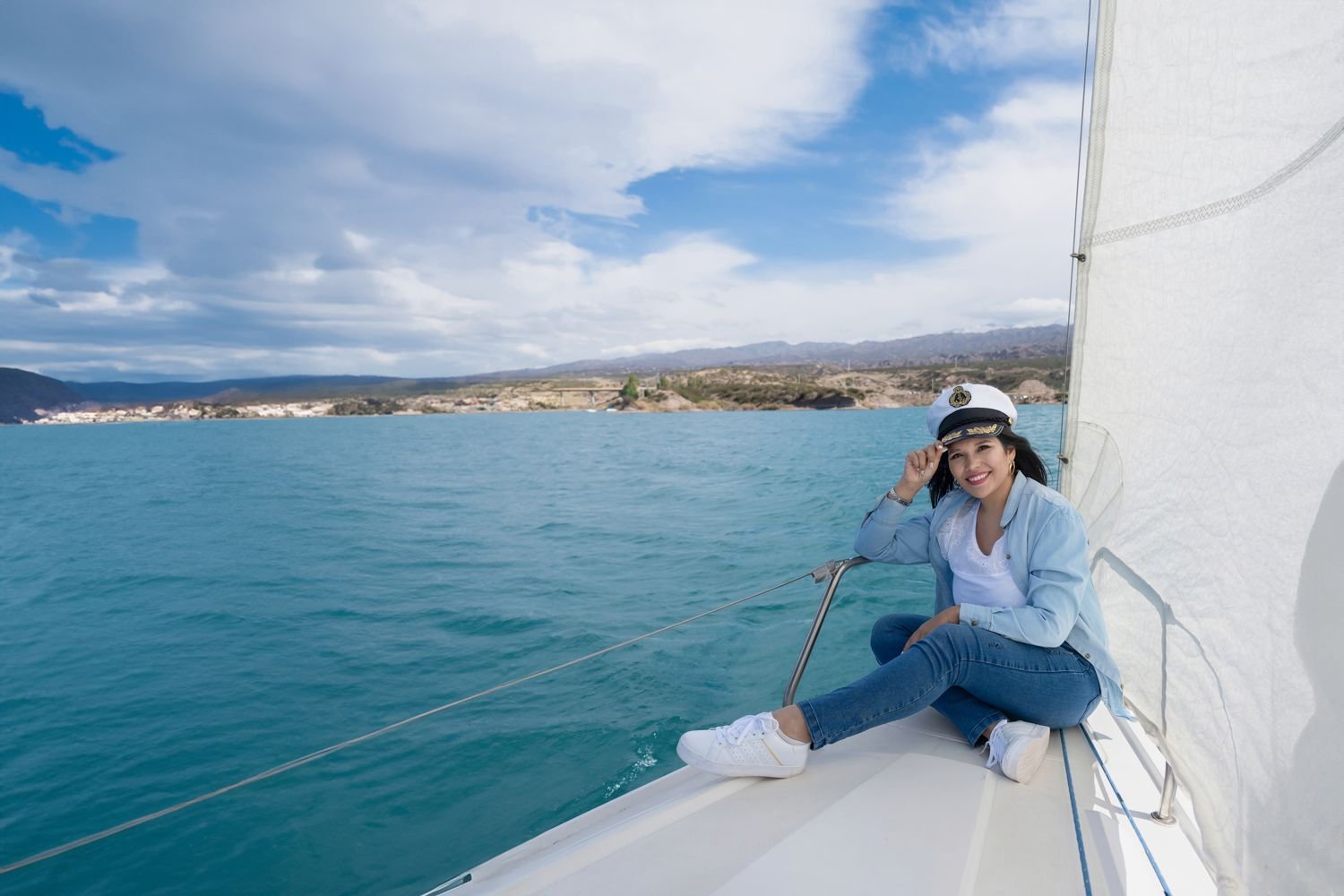 Clienta con gorra de capitán en un velero sobre aguas turquesa en Mendoza