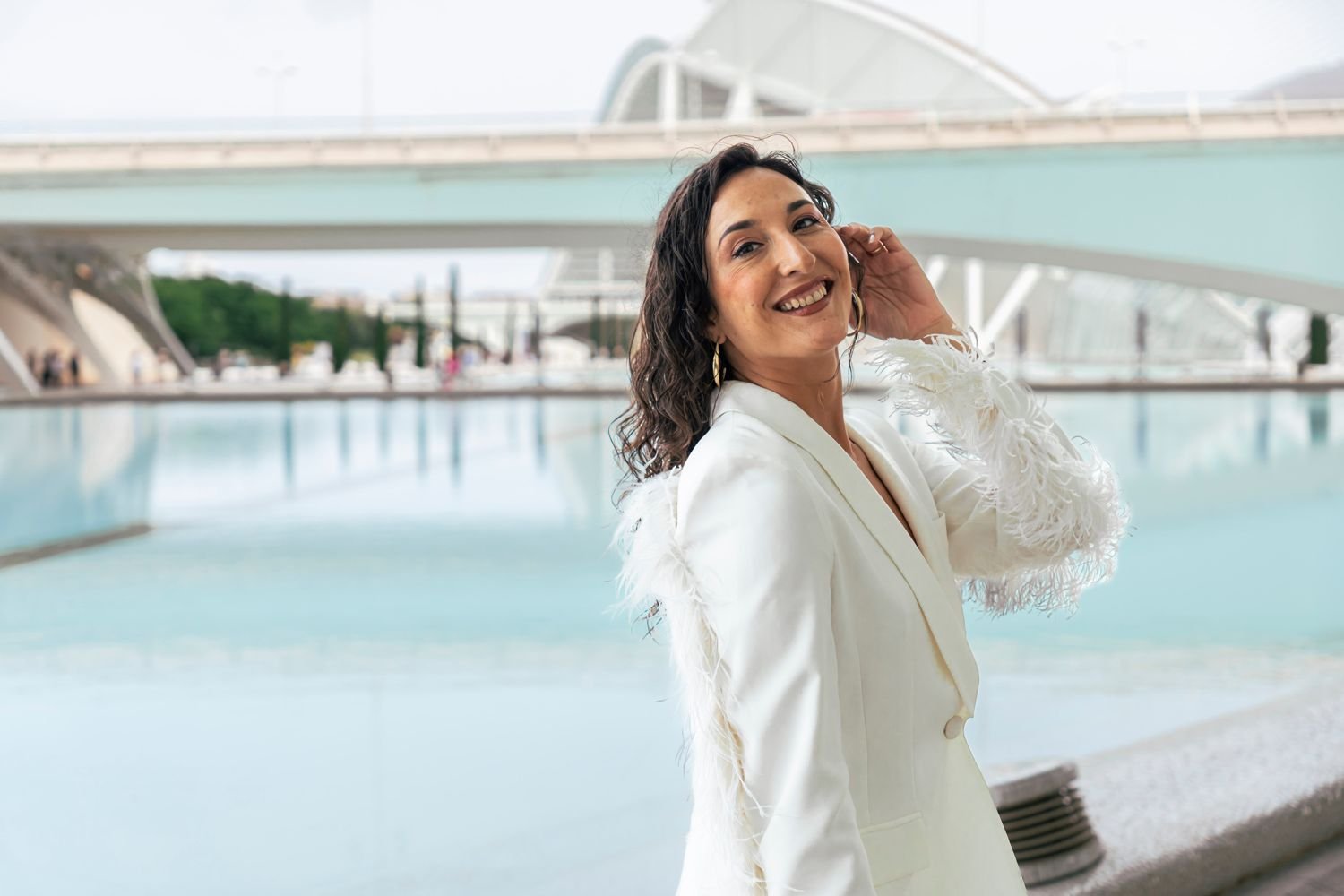 Clienta de blazer blanco junto a un espejo de agua en Valencia