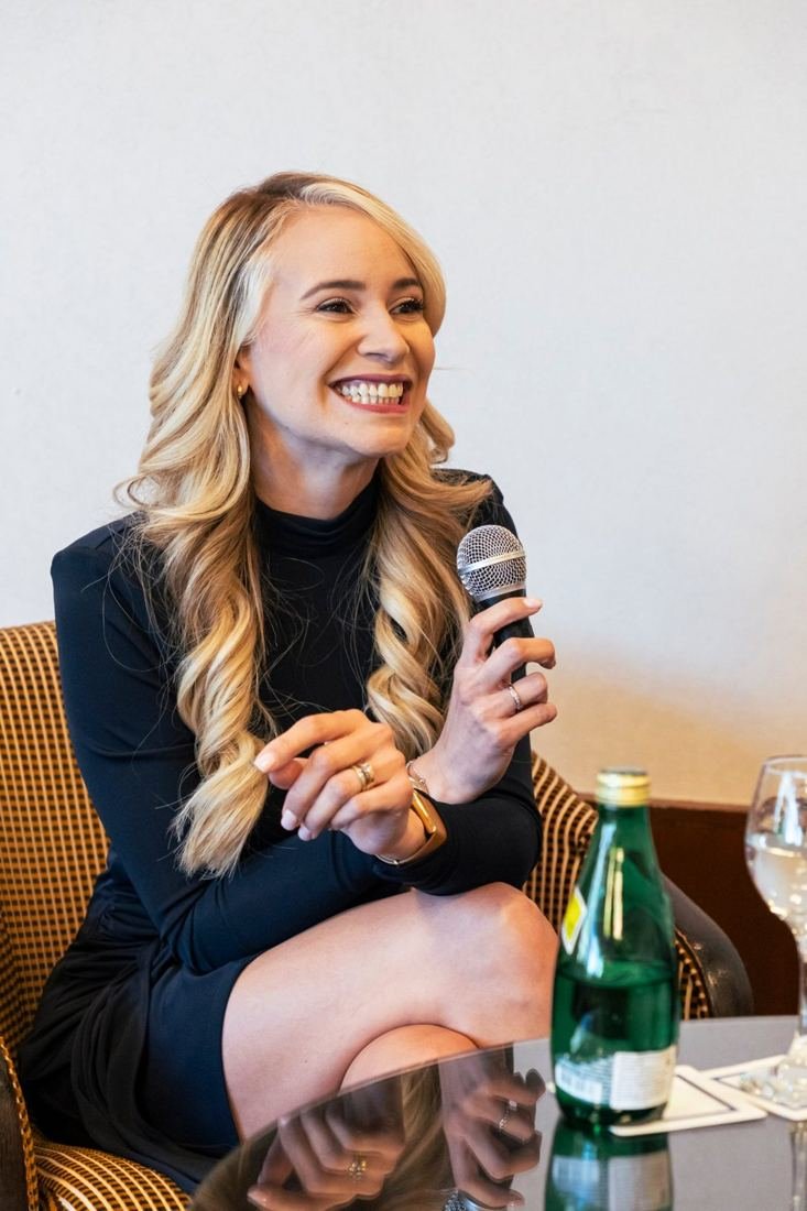 Oradora sonriendo con el micrófono en un panel