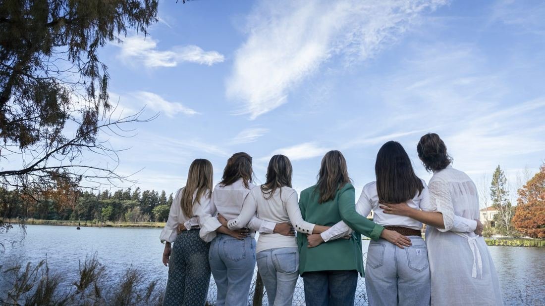 Grupo abrazado frente a un lago